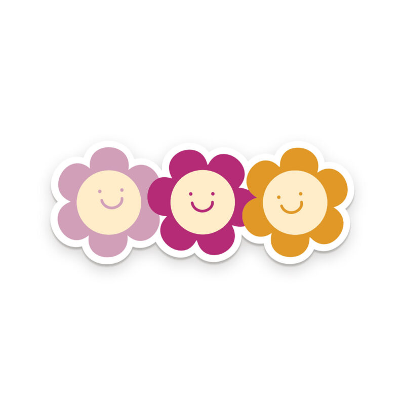 Three smiling flowers, side by side. The first one is mauve, the second, magenta, and the third, golden yellow. The center face of each flower is ivory.